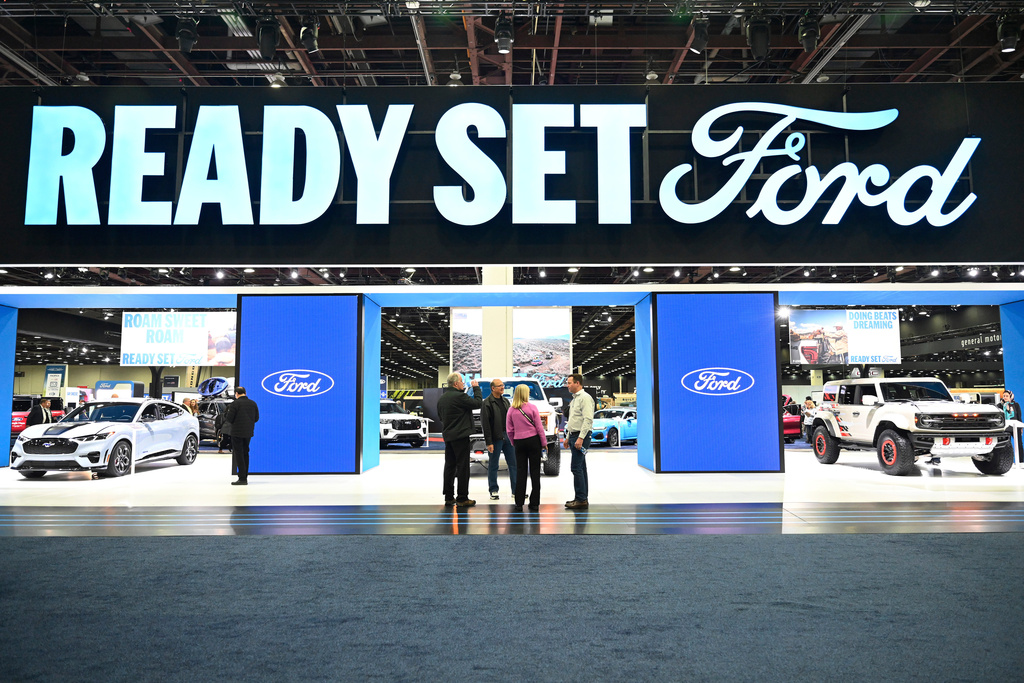 Visitors talk in front of the Ford floor display at the Detroit Auto Show, Wednesday, Jan. 14, 2026, in Detroit. (AP Photo/Jose Juarez)