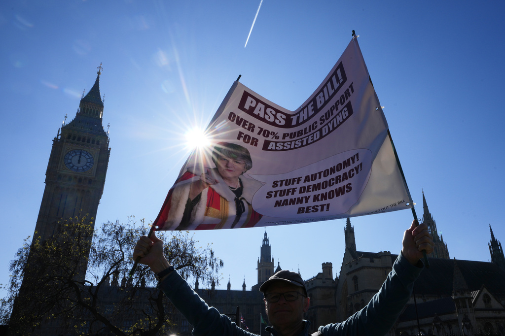 A campaigner holds a banner outside parliament in London as a proposed law to legalise assisted dying in England and Wales will run out of time on Friday, more than a year after MPs first voted in favour of it, Friday, April 24, 2026. (AP Photo/Kirsty Wigglesworth)