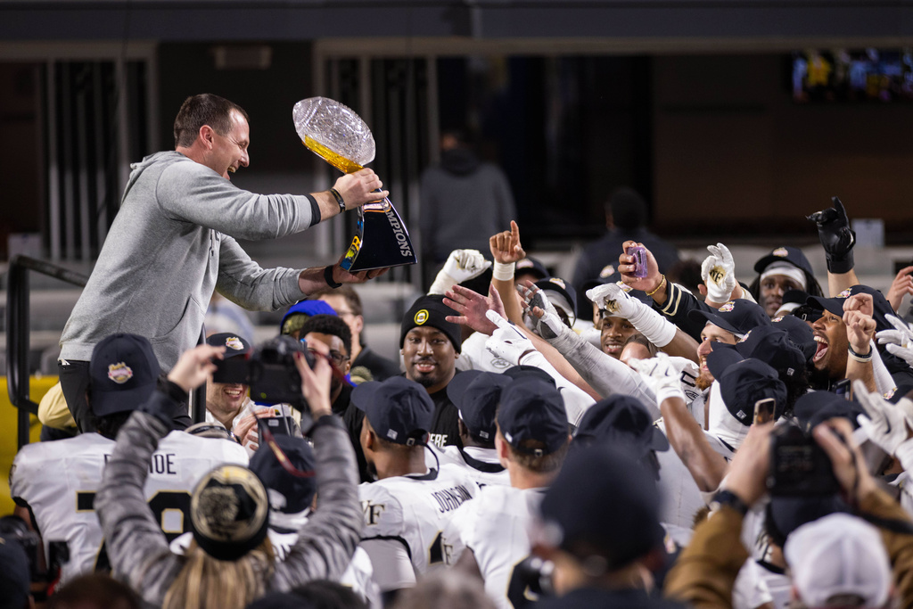 Wake Forest head coach Jake Dickert passes the Duke's Mayo Bowl trophy to his team after an NCAA college football game, Saturday, Jan. 3, 2026, in Charlotte, N.C. (AP Photo/Scott Kinser)