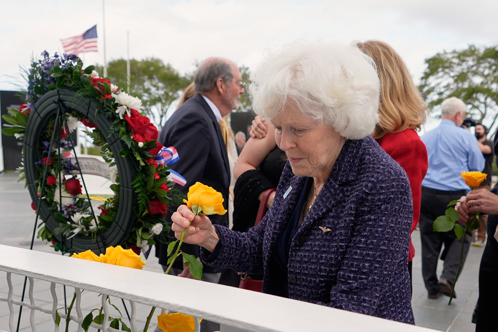 Jane Smith-Wolcott, center, widow of Challenger pilot Michael Smith puts a flower on a memorial during NASA's Day of Remembrance for the 40th Anniversary of the Challenger tragedy at the Kennedy Space Center Visitor Complex in Cape Canaveral, Fla., Thursday, Jan. 22, 2026. (AP Photo/John Raoux)