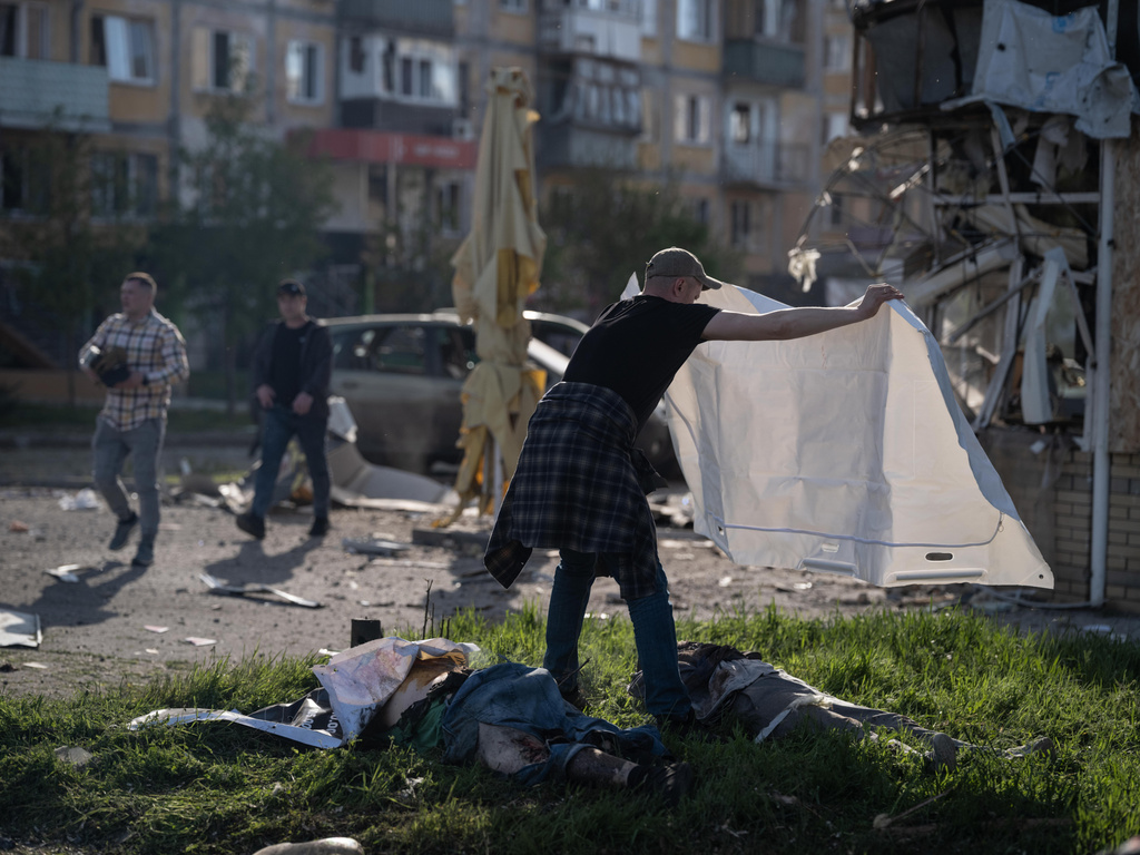 In this photo provided by Ukraine's 93rd Kholodnyi Yar Separate Mechanized Brigade press service, a man covers bodies of civilians killed in Russia's aerial guided bomb attack in Kramatorsk, Donetsk region, Ukraine, Tuesday, May 5, 2026. (Iryna Rybakova/Ukraine's 93rd Mechanized Brigade via AP)