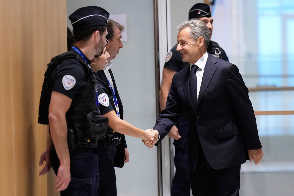 Former French President Nicolas Sarkozy shakes hands with a police officer before his verdict for alleged illegal financing of his 2007 presidential campaign by the government of then-Libyan leader Moammar Gadhafi, Thursday, Sept. 25, 2025 in Paris. (AP Photo/Michel Euler)