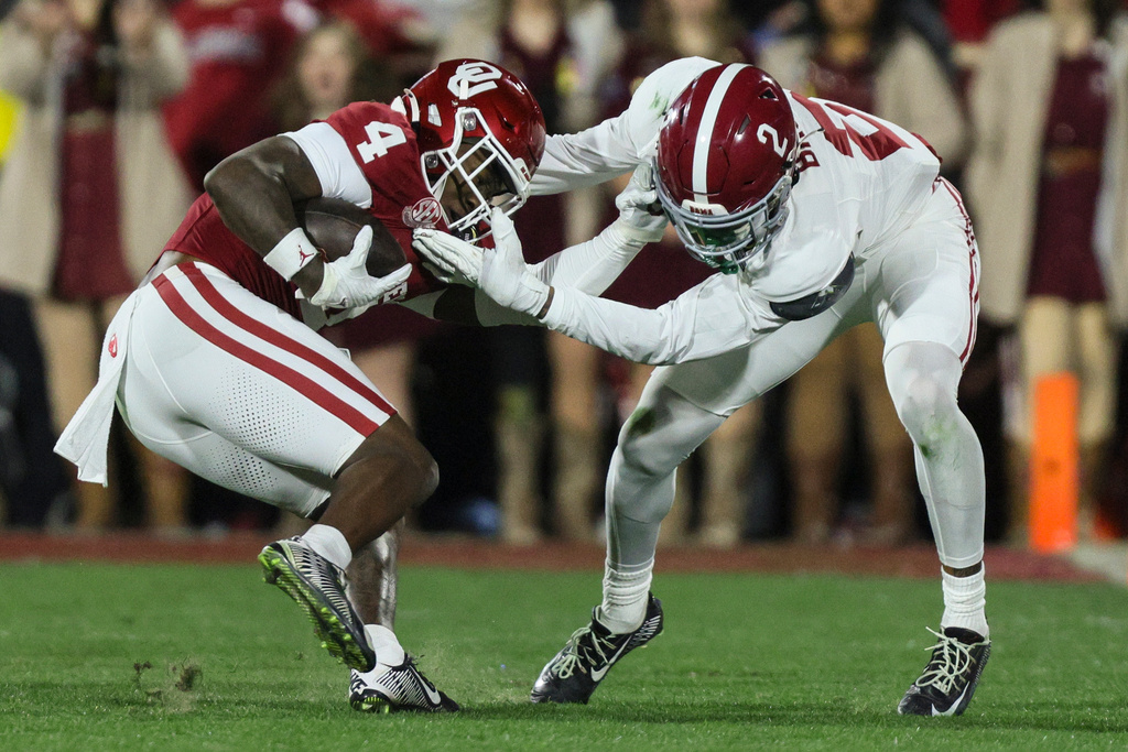 Oklahoma wide receiver Deion Burks (4) is hit by Alabama defensive back Zabien Brown (2) during the first half in the first round of an NCAA College Football Playoff, Friday, Dec. 19, 2025, in Norman, Okla. (AP Photo/Nate Billings)