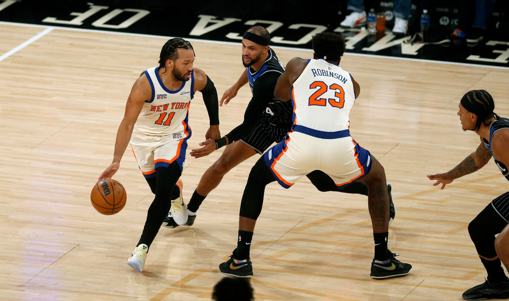 New York Knicks guard Jalen Brunson, left, dribbles around Orlando Magic guard Jalen Suggs, middle, and Knicks center Mitchell Robinson during the first half of an NBA basketball game Sunday, Dec. 7, 2025, in New York. (AP Photo/John Munson)