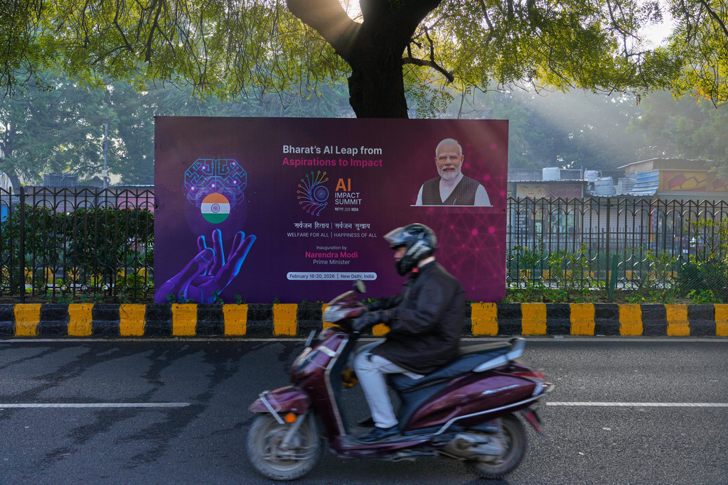 A scooterist drives past a banners of AI-Summit with Indian Prime Minister Narendra Modi stands on a road leading to summit venue in New Delhi, India, Monday, Feb. 16, 2026. (AP Photo/Manish Swarup)