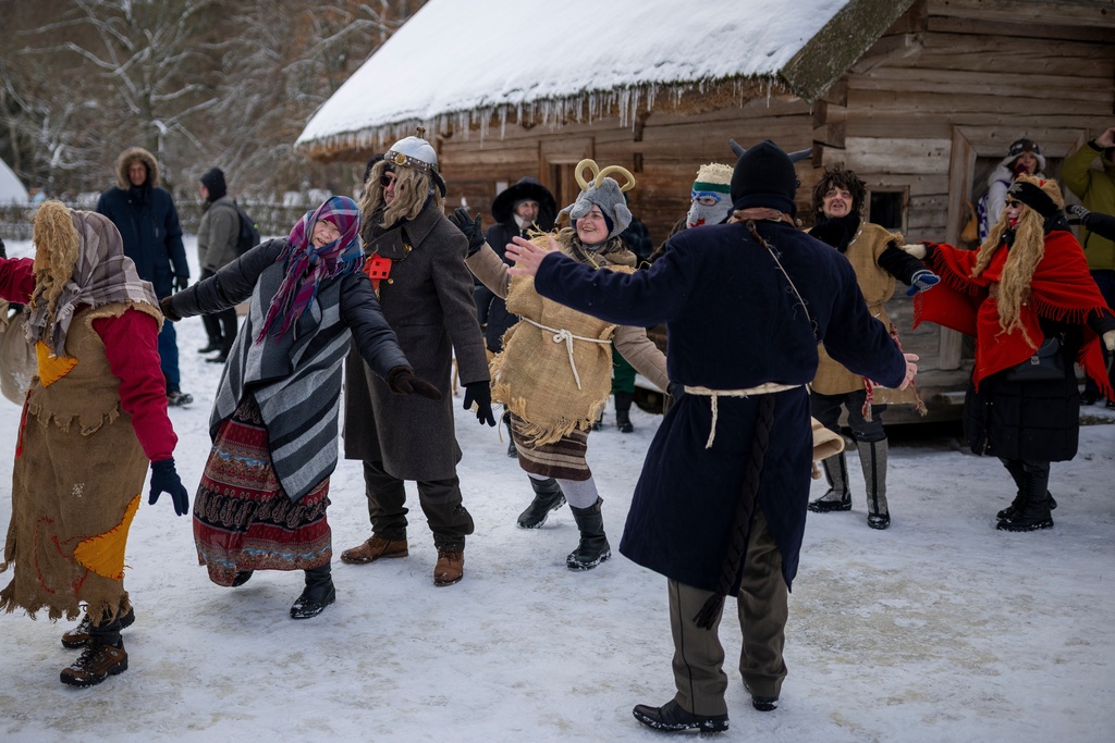 Revelers wearing traditional carnival masks dance during Shrovetide celebrations in the village of Rumsiskes, some 89 kilometers (56 miles) north of Vilnius, Lithuania, Saturday, Feb. 14, 2026. (AP Photo/Mindaugas Kulbis)