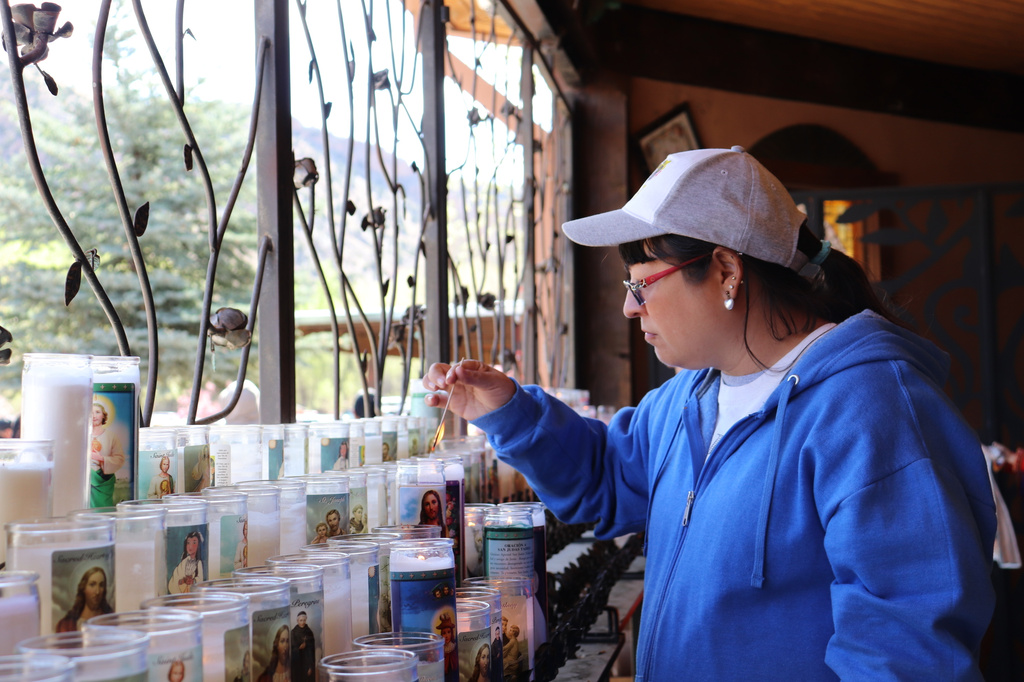 Janelle Montoya lights candles outside El Santuario de Chimayó for the Good Friday pilgrimage in Chimayó, New Mexico, on Friday, April 3, 2026. (AP Photo/Savannah Peters)