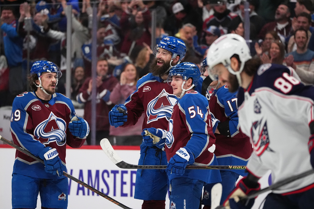 Colorado Avalanche defenseman Brent Burns, second from left, is congratulated after scoring a goal by, from left, defenseman Samuel Girard, and center Gavin Brindley as Columbus Blue Jackets right wing Kirill Marchenko passes byin the first period of an NHL hockey game Saturday, Jan. 10, 2026, in Denver. (AP Photo/David Zalubowski)