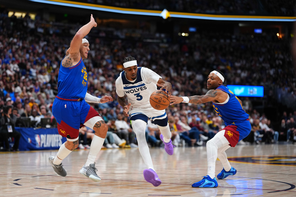 Minnesota Timberwolves forward Jaden McDaniels (3) drives to the basket against Denver Nuggets forward Aaron Gordon (32) and Bruce Brown (11) during the second half in Game 2 of a first-round NBA playoffs basketball series Monday, April 20, 2026, in Denver. (AP Photo/Jack Dempsey)