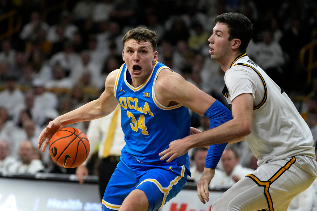 UCLA forward Tyler Bilodeau (34) drives past Iowa forward Alvaro Folgueiras (7) during the first half of an NCAA college basketball game, Saturday, Jan. 3, 2026, in Iowa City, Iowa. (AP Photo/Charlie Neibergall)