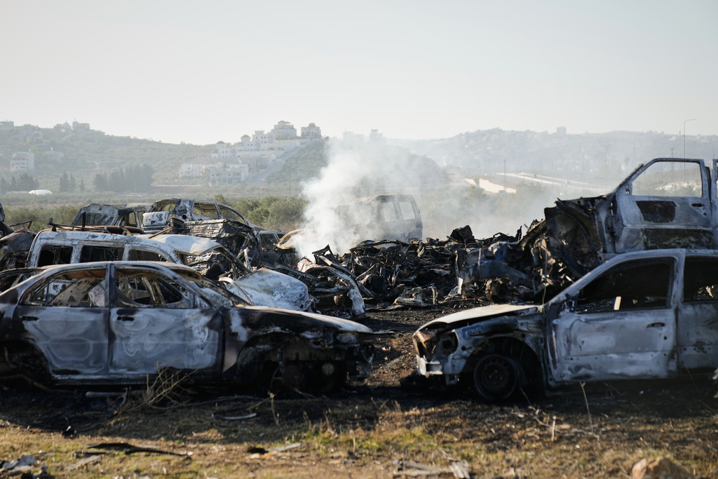 Smoke rises from scorched cars in a scrapyard that was set ablaze the night before by who local residents alleged were Israeli settlers in the town of Huwara near the West Bank city of Nablus, Friday, Nov. 21, 2025. (AP Photo/Nasser Nasser)