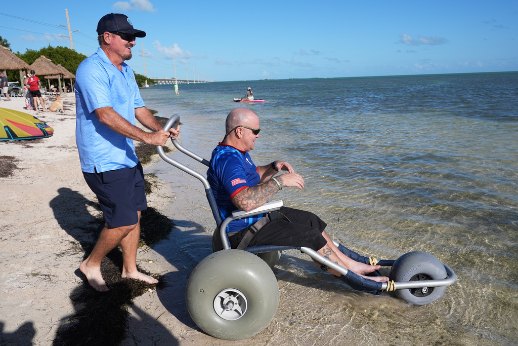 U.S. Navy veteran Jerry Padgett, right, is wheeled into the ocean at the Veterans Memorial Park after riding in the annual Florida Keys Soldier Ride organized by the Wounded Warrior Project, Friday, Jan. 9, 2026, in Little Duck Key, Fla. (AP Photo/Lynne Sladky)