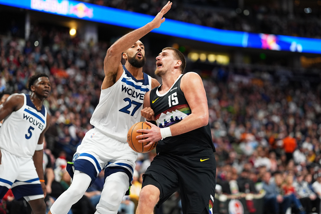 Denver Nuggets center Nikola Jokić, right, drives to the basket as Minnesota Timberwolves center Rudy Gobert defends in the first half of an NBA basketball game, Thursday, Dec. 25, 2025, in Denver. (AP Photo/David Zalubowski)