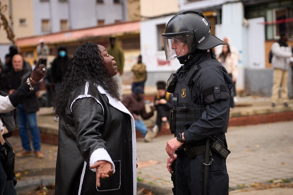 A migrant argues with a riot police officer as police begin carrying out eviction orders at an abandoned school building where hundreds of mostly undocumented migrants had been living, in Badalona, near Barcelona, Spain, Wednesday, Dec. 17, 2025. (AP Photo/Emilio Morenatti)