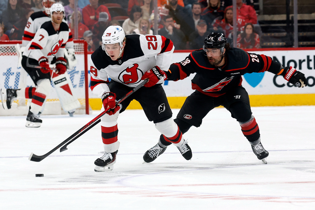 Carolina Hurricanes' William Carrier (28) tries to take the puck from New Jersey Devils' Lenni Hameenaho (29) during the first period of an NHL hockey game in Raleigh, N.C., Saturday, March 28, 2026. (AP Photo/Karl DeBlaker)
