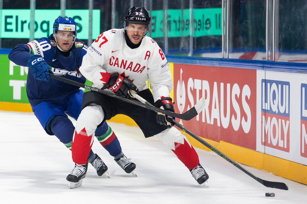 Italy's Peter Spornberger, left, vies for the puck against Canada's Sidney Crosby, right, during the 2026 IIHF Men's Ice Hockey World Championship preliminary round group B game between Italy and Canada, in Fribourg, Switzerland, Saturday, May 16, 2026. (Cyril Zingaro/Keystone via AP)