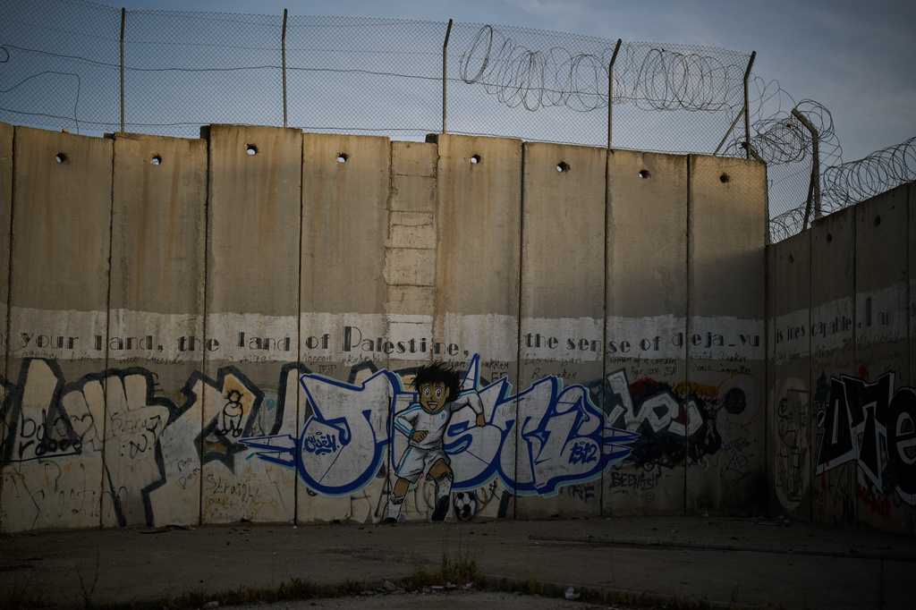 A mural of a youth running with a soccer ball covers Israel's separation wall in the West Bank town of Al-Ram, Monday, May 11, 2026. (AP Photo/Leo Correa)