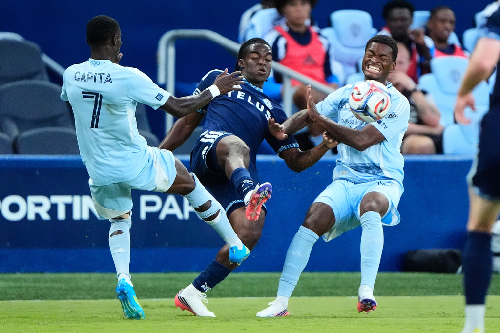 Vancouver Whitecaps' Bruno Caicedo, center, kicks the ball under pressure from Sporting Kansas City's Capita Capemba (7) and Justin Reynolds during the first half of an MLS soccer match Saturday, Aug. 29, 2026, in Kansas City, Kan. (AP Photo/Charlie Riedel)
