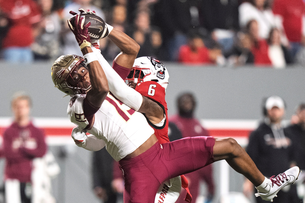 Florida State wide receiver Jayvan Boggs (15) catches a pass over North Carolina State defensive back Devon Marshall (6) during the first half of an NCAA college football game Friday, Nov. 21, 2025, in Raleigh, N.C. (AP Photo/David Yeazell)