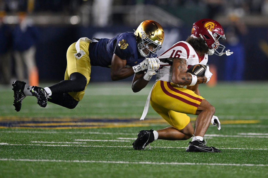 Southern California wide receiver Tanook Hines (16) rushes against Notre Dame's Christian Gray, left, after catching a pass during the first quarter of an NCAA college football game Saturday, Oct. 18, 2025, in South Bend, Ind. (AP Photo/Paul Beaty)