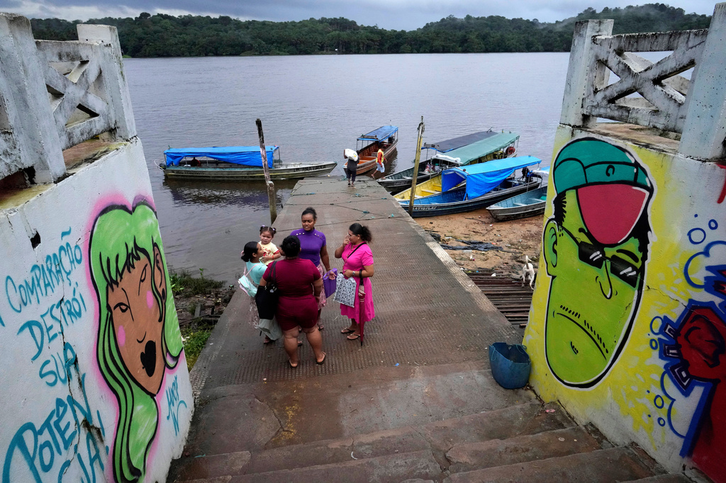 A family talks as they arrive at a port on the banks of the Oiapoque River, in the city of Oiapoque, Amapa state, Brazil, Monday, March 9, 2026. (AP Photo/Eraldo Peres)