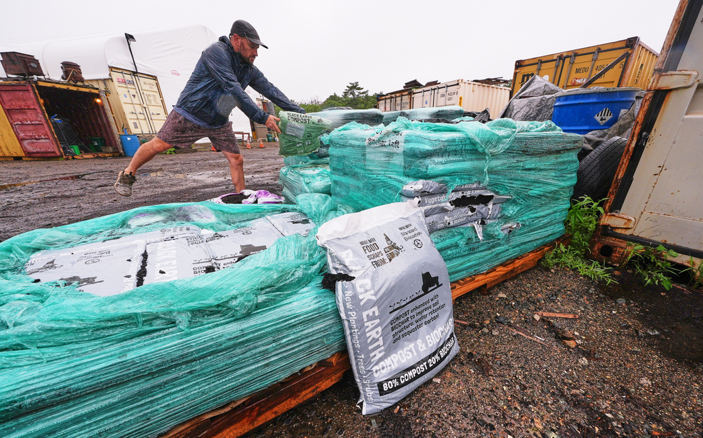 Justin Sandler adds a bag of compost to a pallet at Black Earth Compost, Monday, Aug. 3, 2026, in Manchester-by-the-Sea, Mass. (AP Photo/Charles Krupa)