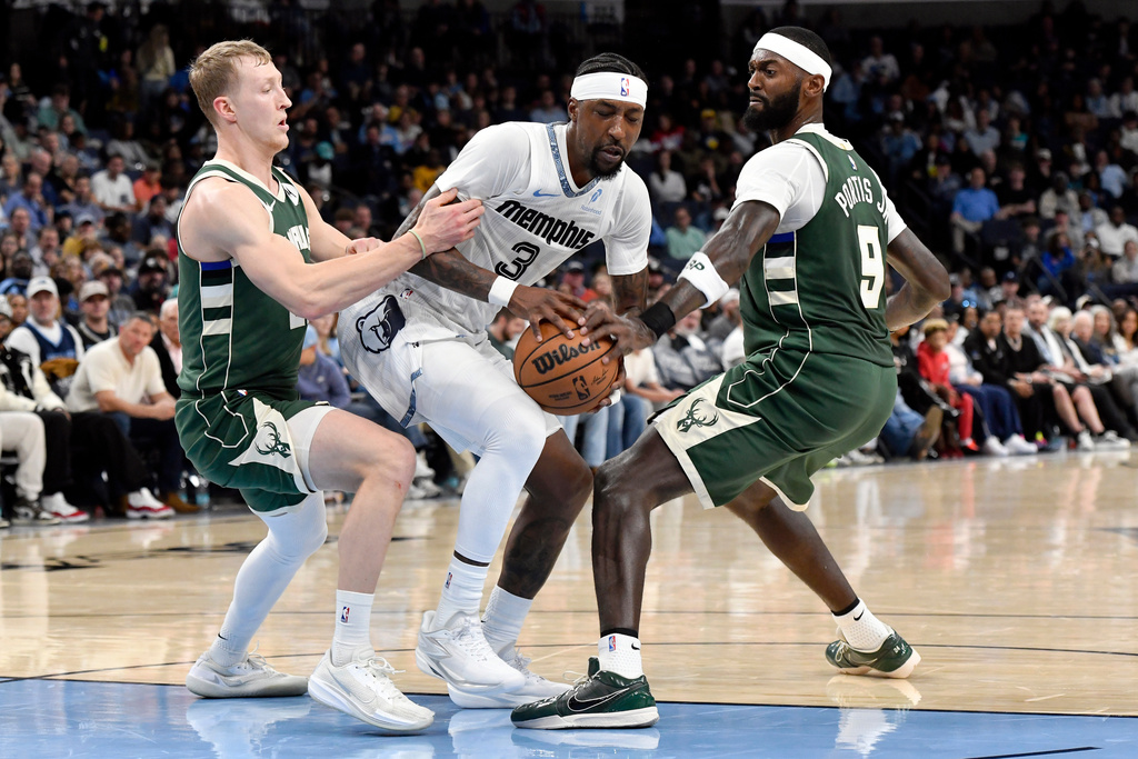 Memphis Grizzlies guard Kentavious Caldwell-Pope (3) handles the ball between Milwaukee Bucks guard AJ Green, left, and forward Bobby Portis (9) in the first half of an NBA basketball game, Friday, Dec. 26, 2025, in Memphis, Tenn. (AP Photo/Brandon Dill)