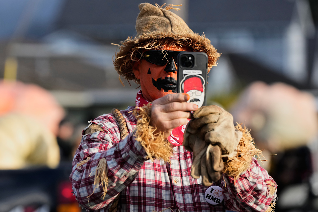 Norman Breshears, dressed up as a scarecrow, takes a photo of one of the giant pumpkins at the 52nd annual World Championship Pumpkin Weigh-Off in Half Moon Bay, Calif., Monday, Oct. 13, 2025. (AP Photo/Godofredo A. Vásquez)