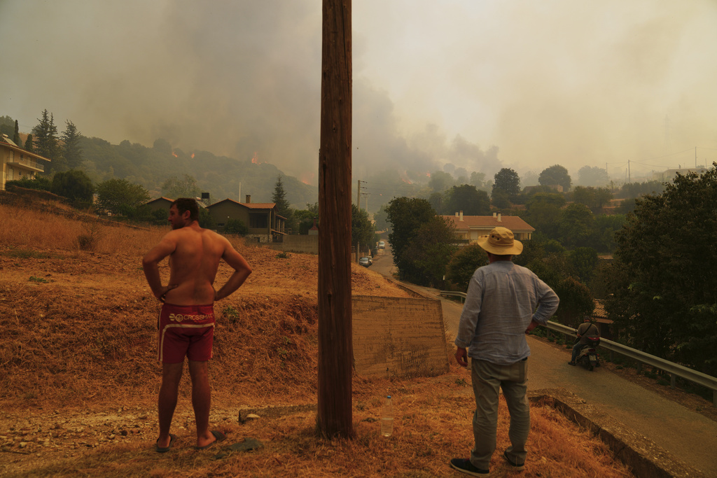 People watch a wildfire in Vounteni village, on the outskirts of Patras, western Greece, Wednesday, Aug. 13, 2025. (AP Photo/Thanassis Stavrakis)
