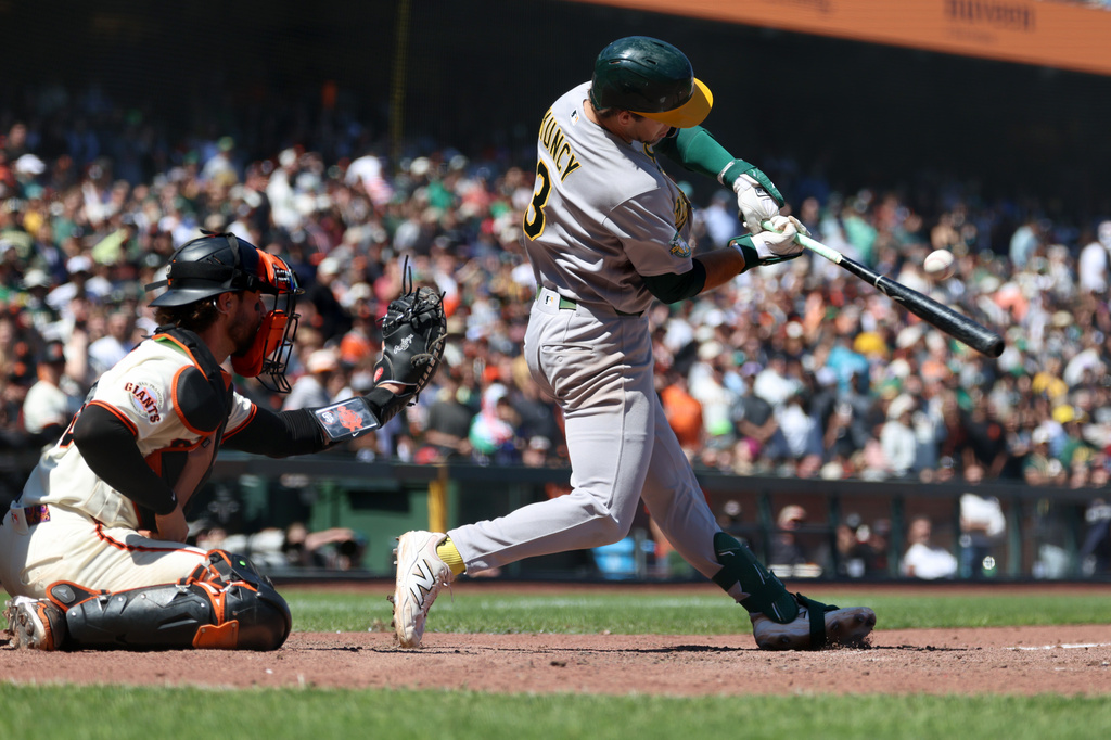 Athletics' Max Muncy, right, hits a two-run single in front of San Francisco Giants catcher Eric Haase, left, during the ninth inning of a baseball game in San Francisco, Thursday, June 25, 2026. (AP Photo/Jed Jacobsohn)