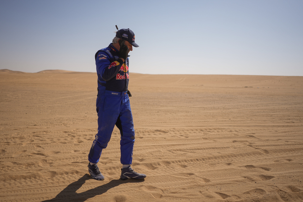 Driver Carlos Sainz gives a phone call at the end of the ninth stage of the Dakar Rally between Wadi Ad Dawasir and Bisha, Saudi Arabia, Tuesday, Jan.13, 2026. (AP Photo/Thibault Camus)