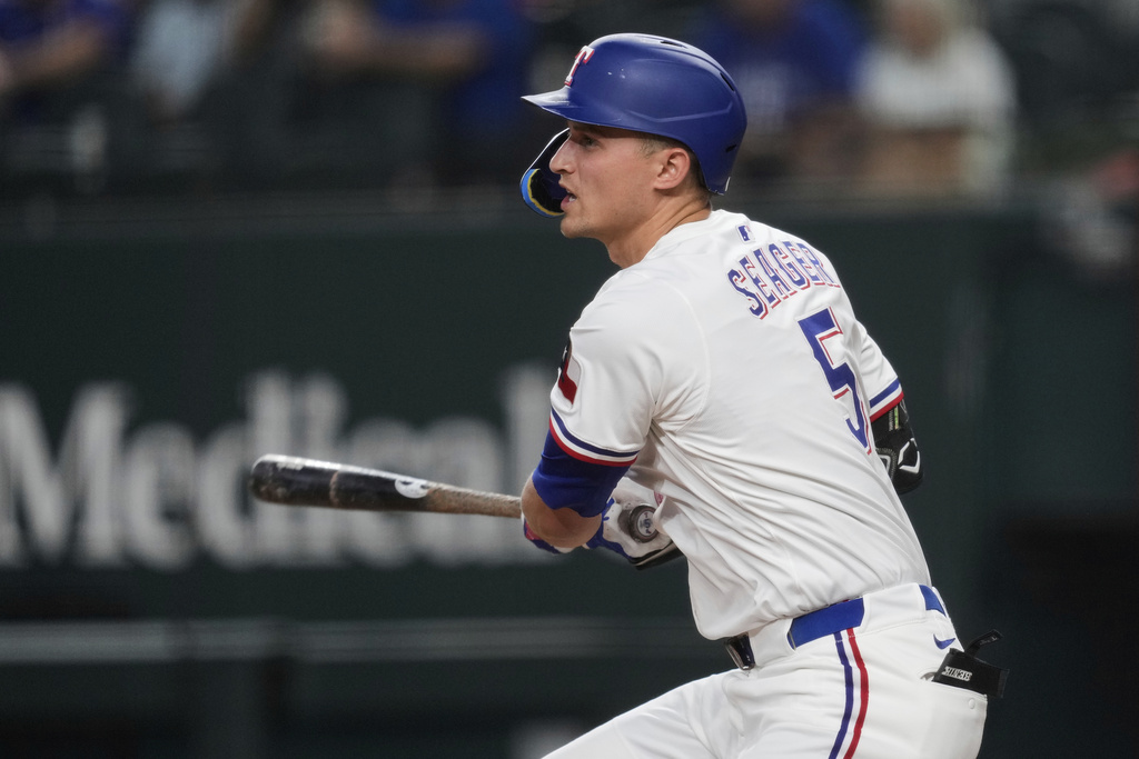 Texas Rangers' Corey Seager follows through on a single in the first inning of a baseball game against the Los Angeles Angels, Wednesday, Aug. 27, 2025, in Arlington, Texas. (AP Photo/Tony Gutierrez)