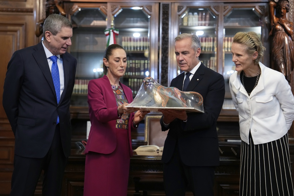 Jesus Maria Tarriba, left, and Diana Fox Carney, right, look on as Mexican President Claudia Sheinbaum presents a gift to Canada's Prime Minister Mark Carney at the National Palace in Mexico City, Thursday, Sept. 18, 2025. (Adrian Wyld/The Canadian Press via AP)