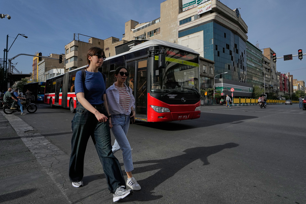 Women walk as a public bus drive in an intersection in downtown Tehran, Iran, Thursday, May 28, 2026. (AP Photo/Vahid Salemi)