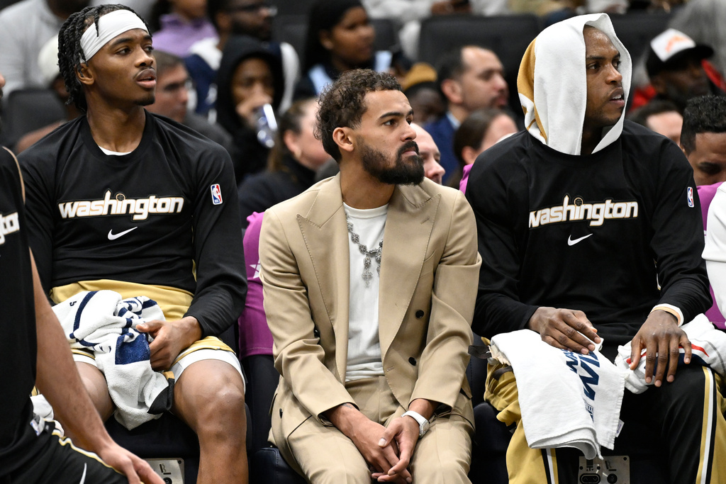 Washington Wizards newly acquired point guard Trae Young, center, sits on the bench in street clothes between guard Bilal Coulibaly, left, and forward Khris Middleton during the first half of an NBA basketball game against the New Orleans Pelicans, Friday, Jan. 9, 2026, in Washington. (AP Photo/John McDonnell)