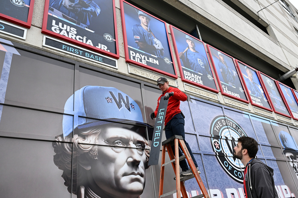 Worker set name plates along a wall for the starting lineup for the Washington Nationals' home-opener baseball game against the Los Angeles Dodgers, Friday, April 3, 2026, in Washington. (AP Photo/Terrance Williams)