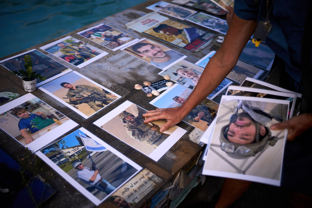 Activists place photos of Israelis who were killed in the Oct. 7, 2023 deadly Hamas attack on Israel, at a memorial marking two years anniversary of the assault, in Tel Aviv, Israel, Tuesday, Oct. 7, 2025. (AP Photo/Emilio Morenatti)