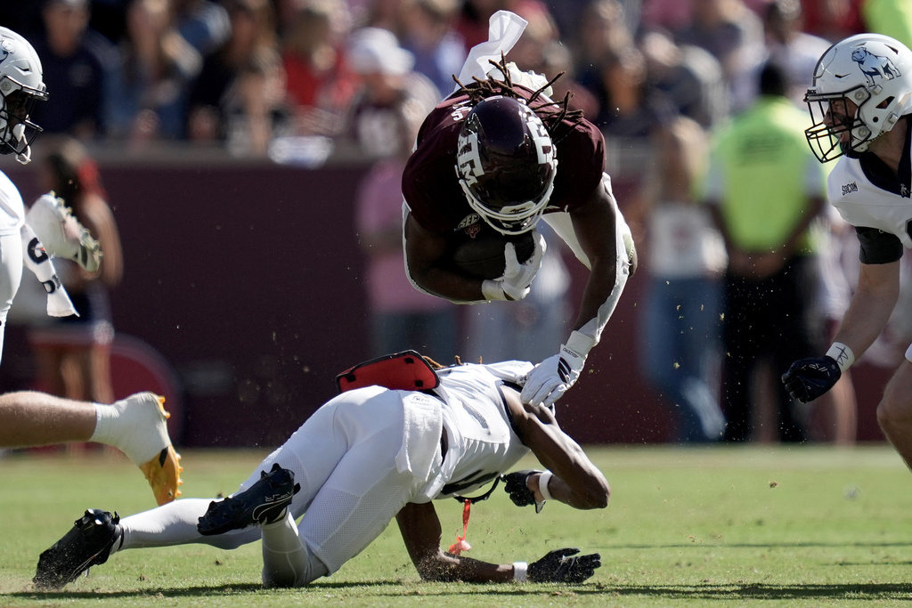 Texas A&M running back Amari Daniels (5) is knocked off his feet at the lne by Samford defensive back Lashon Young (9) during the second quarter of an NCAA college football game Saturday, Nov. 22, 2025, in College Station, Texas. (AP Photo/Sam Craft)