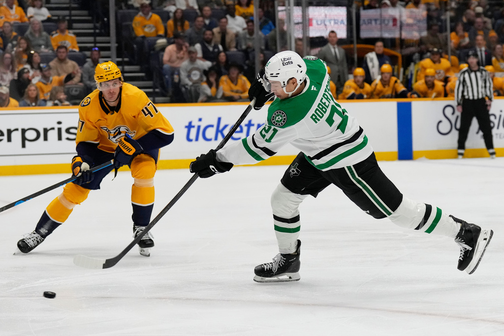 Dallas Stars left wing Jason Robertson (21) gets a shot away as he is defended by Nashville Predators right wing Michael McCarron (47) during the first period of an NHL hockey game Saturday, Nov. 8, 2025, in Nashville, Tenn. (AP Photo/Mark Humphrey)