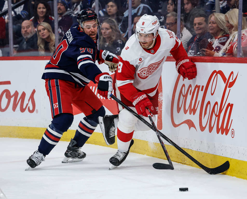 Detroit Red Wings' Ben Chiarot (8) battles for the puck with Winnipeg Jets' Tanner Pearson (70) during the second period of an NHL game in Winnipeg, Saturday, Jan. 24, 2026. (John Woods/The Canadian Press via AP)