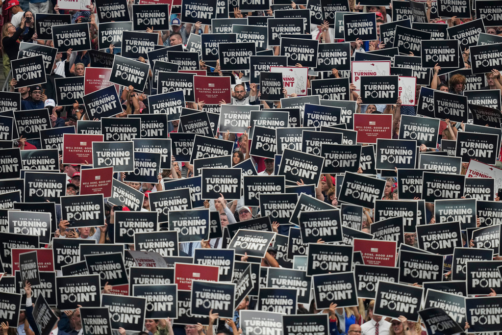 People hold up signs during a memorial for conservative activist Charlie Kirk, Sept. 21, 2025, at State Farm Stadium in Glendale, Ariz. (AP Photo/John Locher, File)