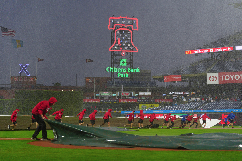 Grounds crew members pull a tarp onto the field during the sixth inning of the second baseball game of a doubleheader between the Philadelphia Phillies and the San Francisco Giants, Thursday, April 30, 2026, in Philadelphia. (AP Photo/Derik Hamilton)