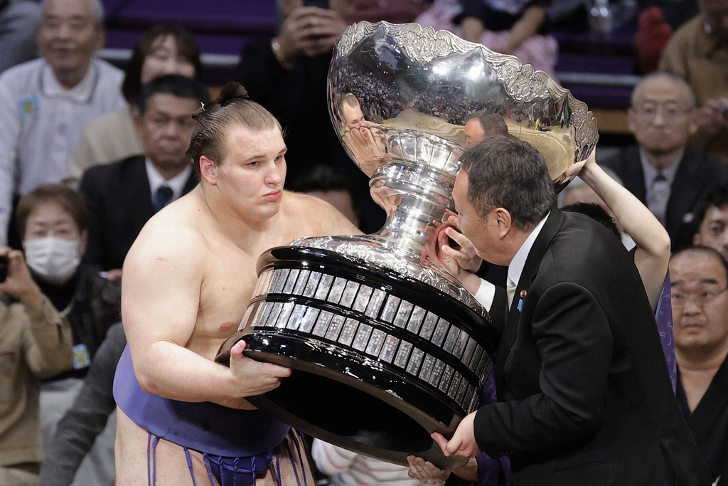 Ukrainian Aonishiki, left, receives a trophy after winning the Kyushu Grand Sumo Tournament in Fukuoka, western Japan, Sunday, Nov. 23, 2025. (Kyodo News via AP)