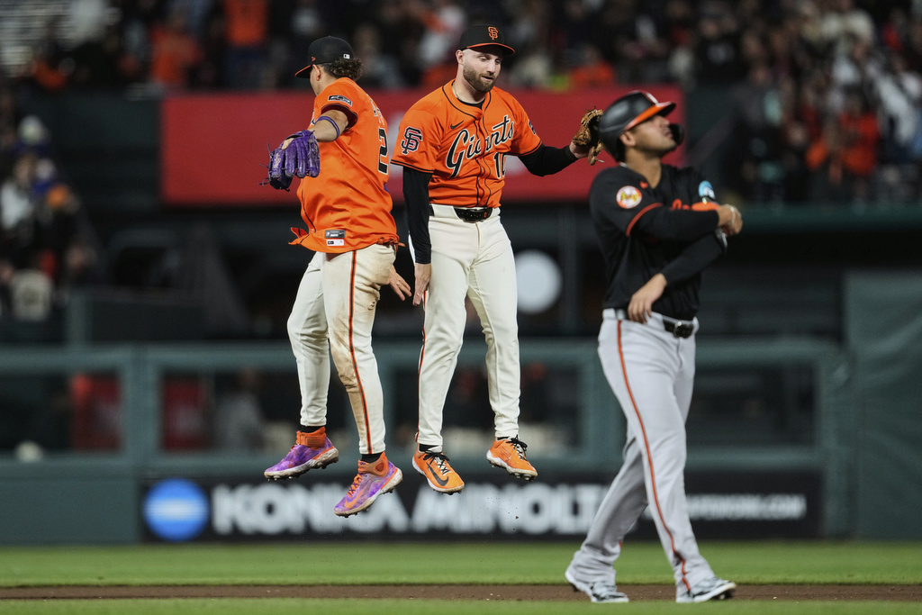San Francisco Giants shortstop Willy Adames, left, and second baseman Casey Schmitt celebrate the team's victory as Baltimore Orioles' Luis Vázquez, foreground, walks off the field after a baseball game, Friday, Aug. 29, 2025, in San Francisco. (AP Photo/Godofredo A. Vásquez)