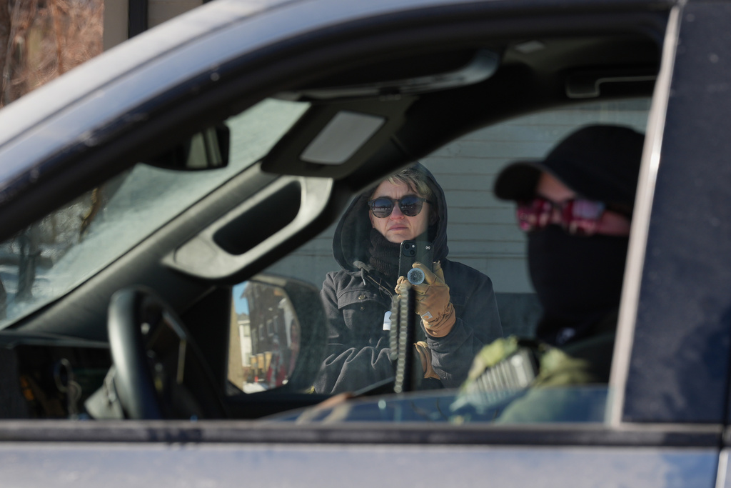 A person photographs a federal agent inside their vehicle on Thursday, Jan. 29, 2026, in North Minneapolis. (AP Photo/Adam Gray)