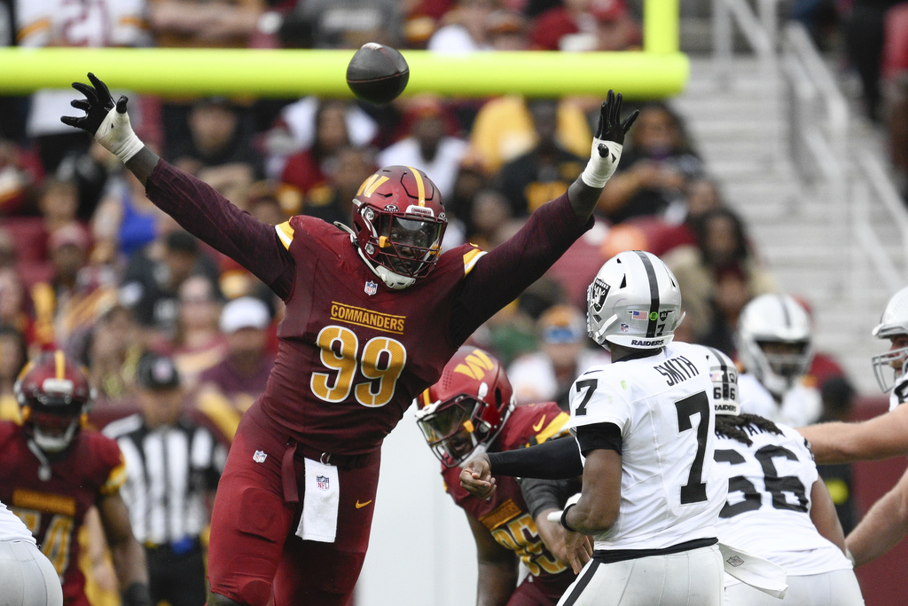 Washington Commanders defensive tackle Javon Kinlaw (99) pressures Las Vegas Raiders quarterback Geno Smith (7) during the second half of NFL football game Sunday, Sept. 21, 2025, in Landover, Md. (AP Photo/Nick Wass)