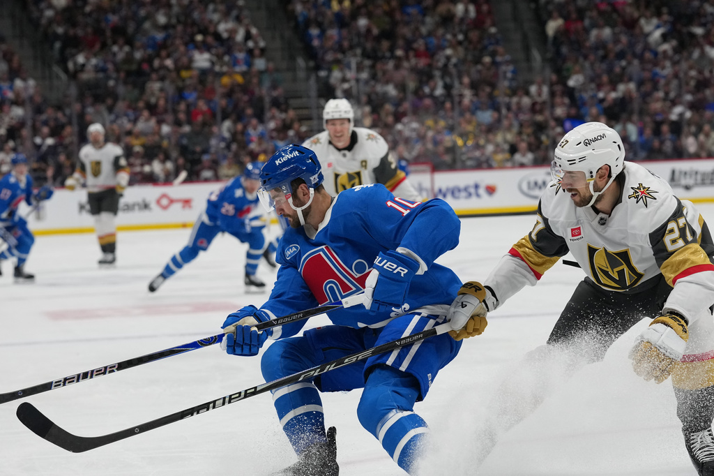 Colorado Avalanche center Nicolas Roy, left, struggles to control the puck as Vegas Golden Knights defenseman Shea Theodore covers in the first period of an NHL hockey game Saturday, April 11, 2026, in Denver. (AP Photo/David Zalubowski)