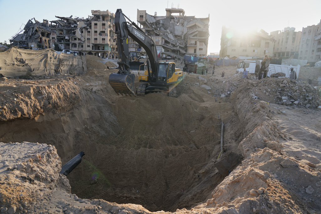Palestinians watch machinery and some workers from Egypt searching for the bodies of hostages at Hamad City, in Khan Younis, southern Gaza Strip, Monday, Oct. 27, 2025. (AP Photo/Jehad Alshrafi)