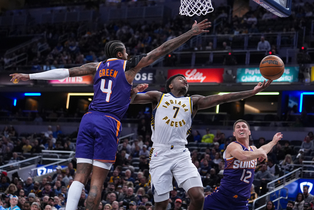 Indiana Pacers guard Kam Jones (7) shoots between Phoenix Suns guard Jalen Green (4) and guard Collin Gillespie (12) during the first half of an NBA basketball game in Indianapolis, Thursday, March 12, 2026. (AP Photo/Michael Conroy)