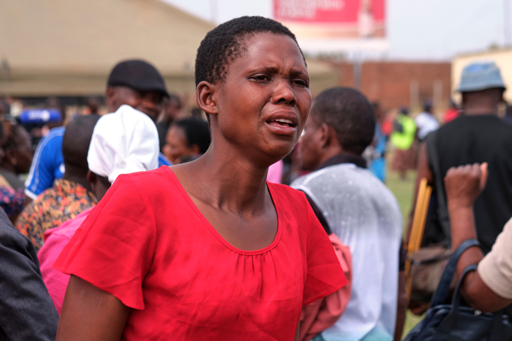 A family member reacts after she sees her father's name on the coffin during a memorial service for the victims of a ferry that capsized on Lake Kariba in Kariba, Zimbabwe, Thursday, Aug. 13, 2026. (AP Photo/Mkhululi Thobela)